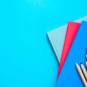 Photo de fournitures scolaires vendues à la Papeterie Valles à Lourdes (65100) dans les Hautes-Pyrénées. Trois cahiers et des crayons de couleur.